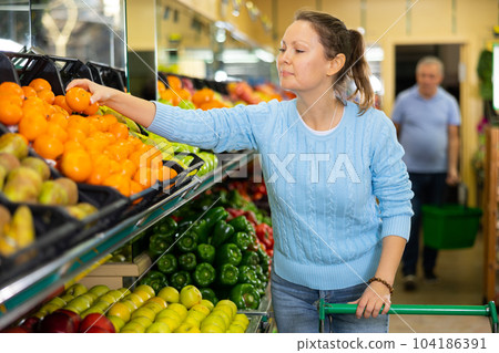 woman buys juicy tangerines in supermarket 104186391