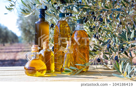 Bottles with olive oil and olive branch on a wooden table 104186419