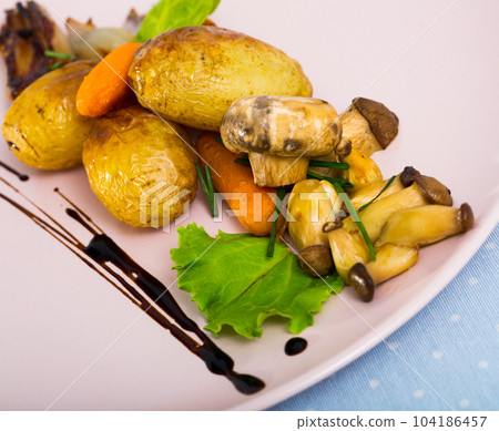 Baked mushrooms with garlic and potatoes, served with caramelized shalot 104186457