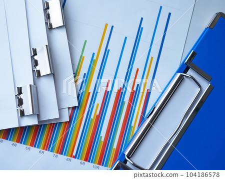 Binders and graphs on the table, documents bound with clips 104186578