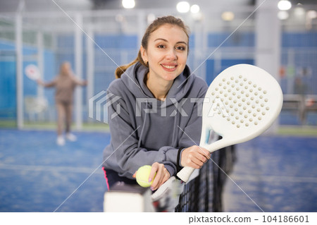 Portrait of a young woman tennis player standing with a padel racket 104186601