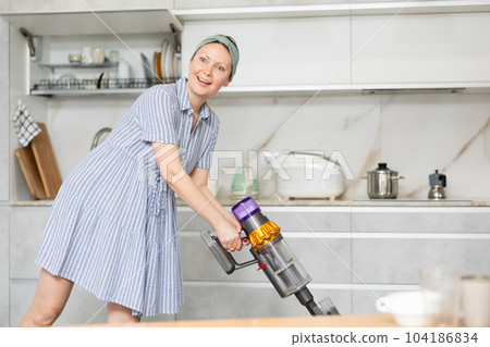 Housewife does cleaning in room - vacuums and dusts 104186834