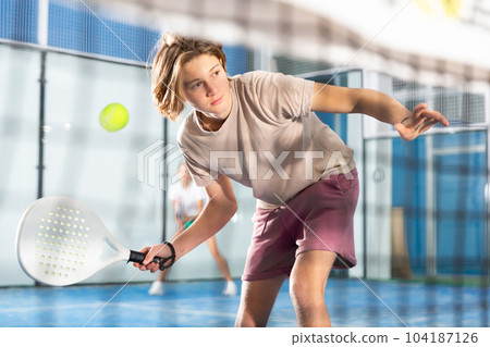 Sportive guy playing padel together with a partner. View through tennis net 104187126