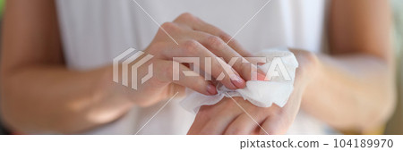 Right hand wipes left hand with piece of damp cloth closeup Right hand wipes left hand with piece of damp cloth closeup 104189970