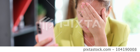 Sad girl upset reading bad news in a mobile message on smartphone in office at table Sad girl upset reading bad news in a mobile message on smartphone in office at table 104190008