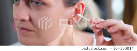 Woman cleans ears with cotton swabs closeup 104190014