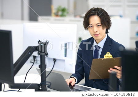 A young businessman in a suit doing desk work 104190618