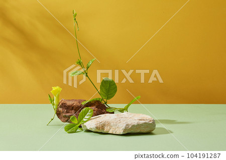 Against a yellow background with natural shadow leaf, two blocks of stone decorated with yellow flower and green leaves. Blank space for design, advertising and branding cosmetic product 104191287