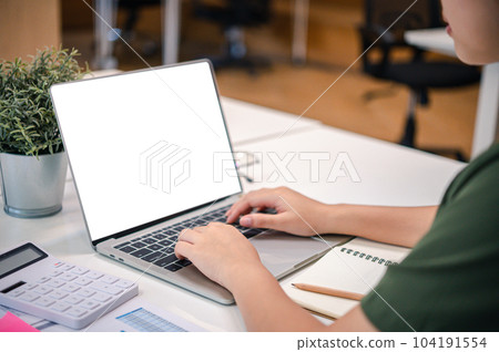 Mockup image of a woman's hand working on a laptop with blank white desktop copy space screen on a desk. 104191554