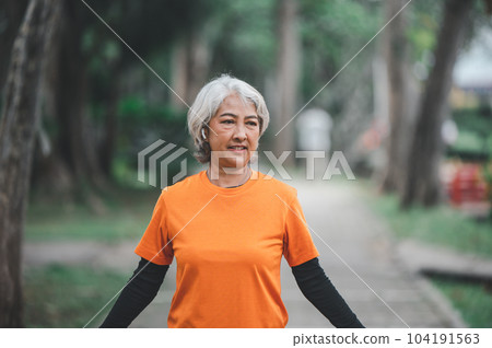 white-haired elderly person exercising in the park early in the morning. 104191563