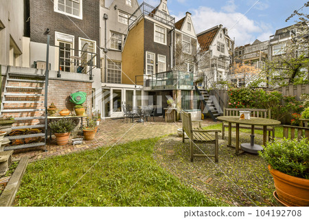 a backyard area with tables and chairs, including an outdoor dining set on the grass in front of the house 104192708