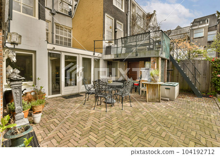 a back yard with patio furniture and outdoor dining set up on brick paversed ground in front of the house a back yard with patio furniture and outdoor dining set up on brick paversed ground in front of the house 104192712