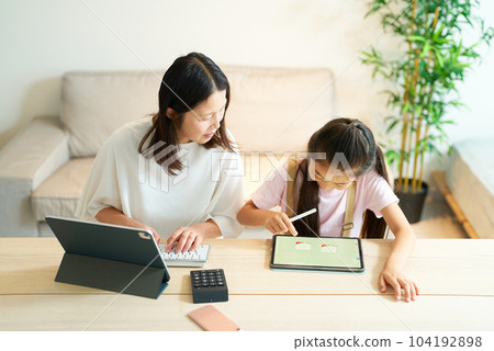 A girl playing with a woman who works using a tablet PC A girl playing with a woman who works using a tablet PC 104192898