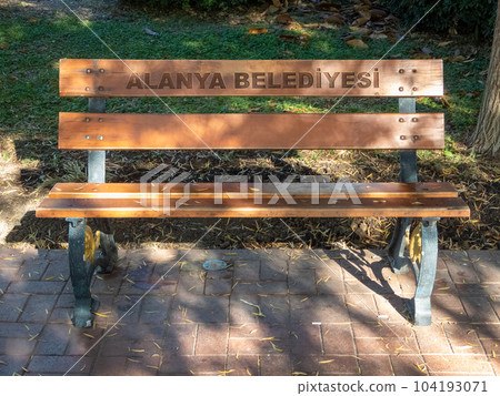 Alanya, Turkey - Nov 3, 2022. Bench in a city park, in patches of sunlight Alanya, Turkey - Nov 3, 2022. Bench in a city park, in patches of sunlight 104193071