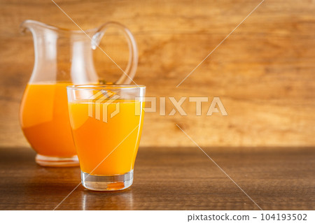 A glass of fruit juice. Orange  juice on wooden table. 104193502