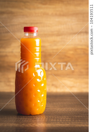 A bottle of fruit juice. Orange  juice on wooden table. 104193511