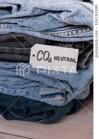 CO2 neutral emission text note on stack of jeans. Ecology nature friendly, climate change, green fuel and earth protect concept. Carbon emission paper recycled label. Natural organic jeans clothing 104193990