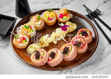 Two types of sushi rolls in mamenori served on plate with ginger 104195347