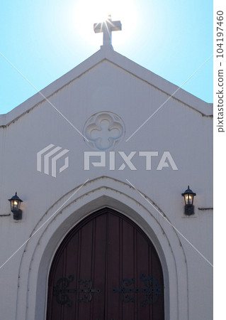 A cross on the roof of a church backlit by the sun 104197460