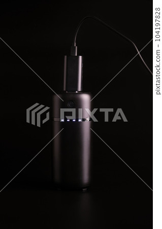 powerbank black on a black background, usb cable, plug, light and reflection powerbank black on a black background, usb cable, plug, light and reflection 104197828