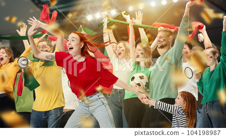 Young people, football fans and little girl, child watching live football match, cheering up favourite sport team. Expressive emotive game Young people, football fans and little girl, child watching live football match, cheering up favourite sport team. Expressive emotive game 104198987