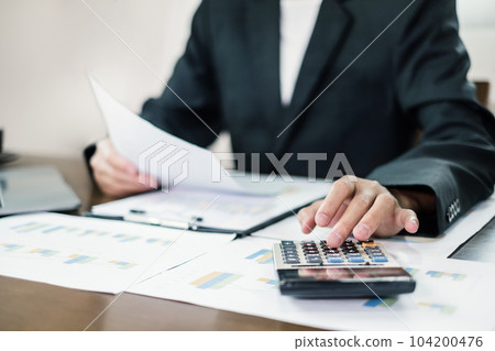The businessman hand sits at their desks and calculates financial graphs showing the results of their investments planning the process of successful business growth The businessman hand sits at their desks and calculates financial graphs showing the results of their investments planning the process of successful business growth 104200476