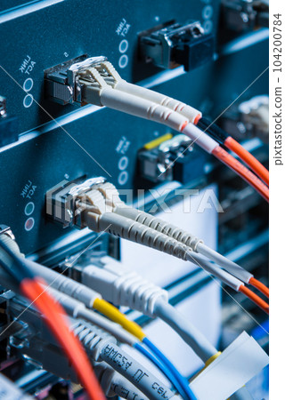 detail of server rack with fiber optic cables attached to front panel switch ports 104200784