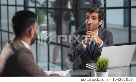 Two smiling businessmen working on a laptop in the office discussing ideas 104201036