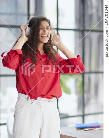 Beautiful smiling young woman in headphones in modern office Beautiful smiling young woman in headphones in modern office 104201044