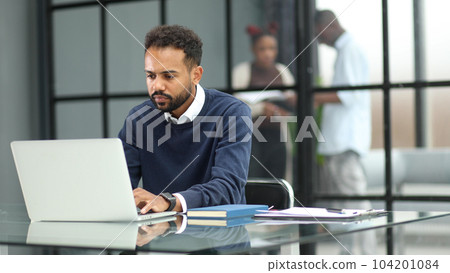 African businessman working on a laptop in an office African businessman working on a laptop in an office 104201084