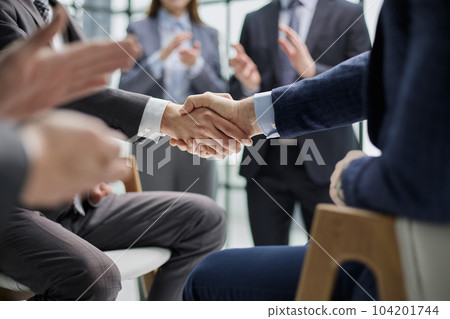 Business colleagues shaking hands in an office hallway 104201744
