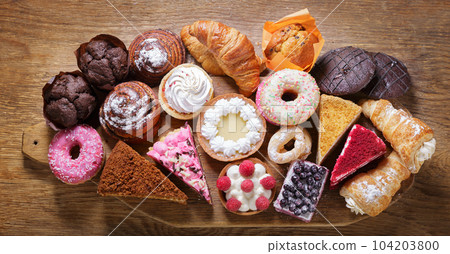 Sweet dessert. Various piece of cakes, muffins and cookies on wooden board 104203800