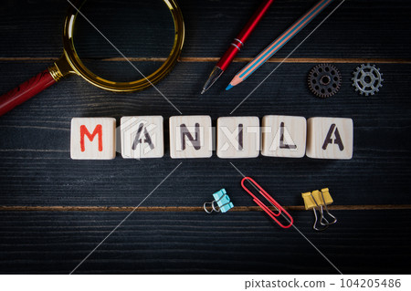 MANILA. City name from blocks on a dark wood texture background 104205486