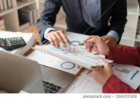 Team of two asian male and female business people working together discussing new financial graph data on office table with laptop and digital tablet. 104205509
