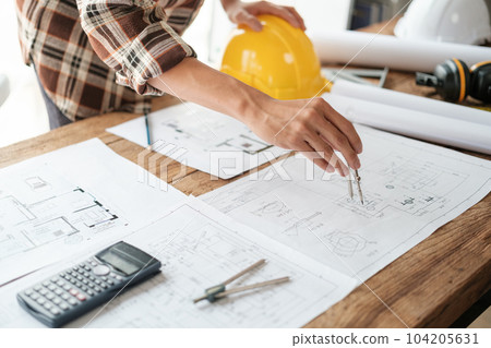 Architects talking at the table Teamwork and Workflow Creation Concepts, Close-up of Person Engineer's Hand Drawn Plan on Blue Print with Architect Equipment. Architects talking at the table Teamwork and Workflow Creation Concepts, Close-up of Person Engineer's Hand Drawn Plan on Blue Print with Architect Equipment. 104205631