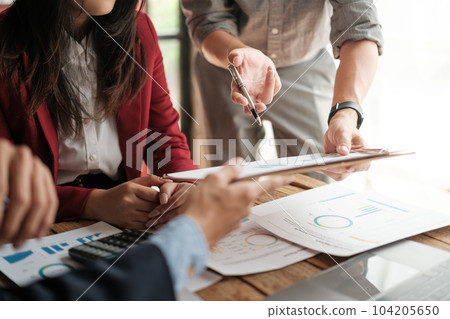 Close up group of business men and woman discussion and brainstorming, bookkeeping audit graph and chart documents at desk, teamwork concept. 104205650