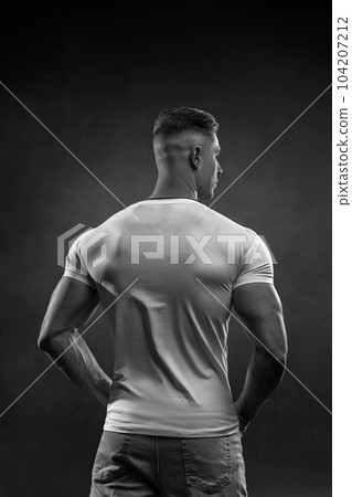 Athletic sexy man in white tight t-shirt posing in studio back view 104207212