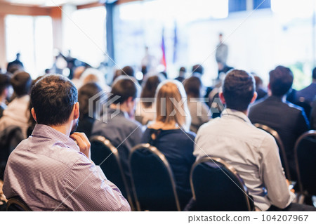 Speaker giving a talk in conference hall at business event. Rear view of unrecognizable people in audience at the conference hall. Business and entrepreneurship concept 104207967