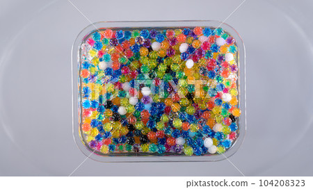 Water beads in box top view, abstract background. Texture of Hydrogel balls or many colorful orbeez for wallpaper. Water beads in box top view, abstract background. Texture of Hydrogel balls or many colorful orbeez for wallpaper. 104208323