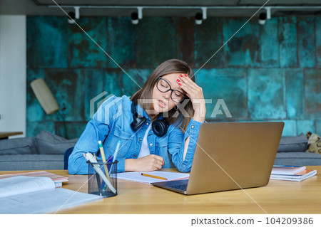 Unhappy sad female university student at home at her desk Unhappy sad female university student at home at her desk 104209386