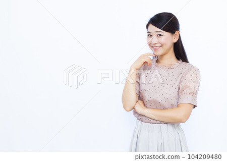 A woman in her thirties thinking with a smile in front of a white background 104209480