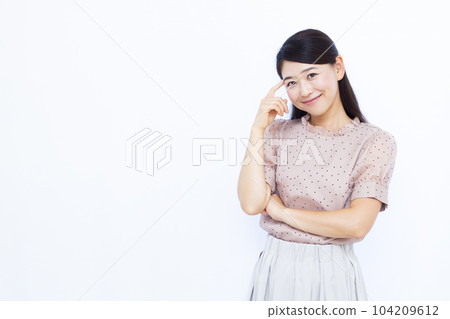 A woman in her thirties thinking with a smile in front of a white background 104209612