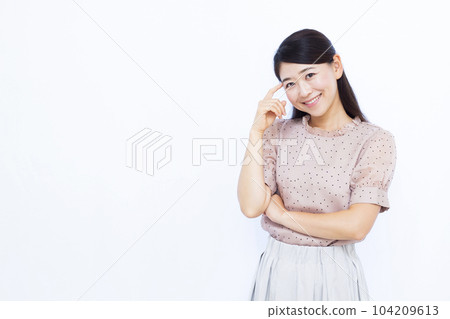A woman in her thirties thinking with a smile in front of a white background 104209613