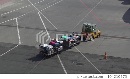 Trailer truck full of suitcases on the runway. Workers carry suitcases to load on the plane. Trailer truck full of suitcases on the runway. Workers carry suitcases to load on the plane. 104210373