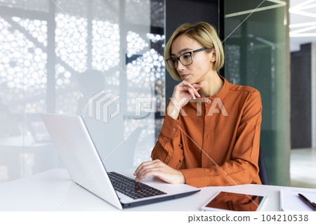 Serious thinking woman working with laptop inside office at workplace, businesswoman solving technical task, female programmer coding new software. Serious thinking woman working with laptop inside office at workplace, businesswoman solving technical task, female programmer coding new software. 104210538