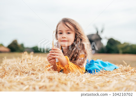 Ukraine's Independence Flag Day. Girl in traditional embroidery with flag of Ukraine in field. Constitution day. 24 August. Patriotic holiday. 104210702