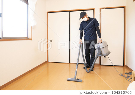 A male worker vacuuming a tidy up room A male worker vacuuming a tidy up room 104210705