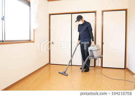 A male worker vacuuming a tidy up room A male worker vacuuming a tidy up room 104210708