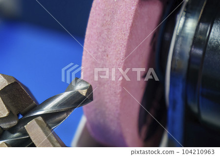 Close up scene the drill tool regrinding process with abrasive stone wheel. 104210963