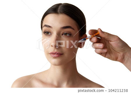 Portrait of young woman taking care after skin, doing cosmetological injections against white studio background Portrait of young woman taking care after skin, doing cosmetological injections against white studio background 104211238
